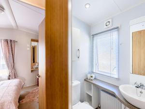 2 Bed in Newborough 82559 في Brynsiencyn: حمام مع مغسلة وسرير في الغرفة