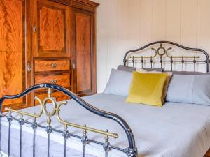 3 Bed in Faversham 78880 في فيفرشام: سرير باللوح المعدني ومخدة صفراء