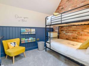 a bedroom with a bunk bed and a yellow chair at 3 Bed in Belper 83037 in Hazelwood