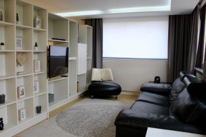a living room with a black leather couch and a television at Strasbourg Entzheim in Entzheim