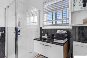 uma casa de banho branca com um lavatório e um chuveiro em crystal blue apartment em Port Vincent