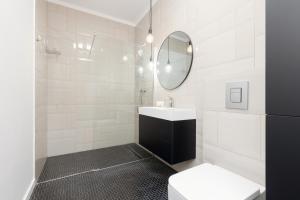 a white bathroom with a sink and a mirror at Minimalist Apartment in Łódź With Parking Near Łódź Kaliska by Renters in Łódź