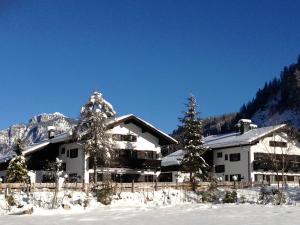 une maison dans la neige devant une montagne dans l'établissement Forsthaus Reit im Winkl, à Reit im Winkl