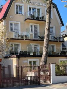 a building with a fence and a tree in front of it at Willa Komandor in Ustka