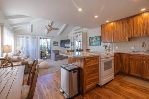 a kitchen with wooden cabinets and a living room at Shores Of Maui 224 in Kihei