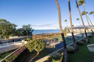 a tennis court with palm trees and the ocean at Shores Of Maui 224 in Kihei