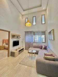 uma sala de estar com um sofá e uma televisão em Take a cosy rest Near the airport em Nouaceur
