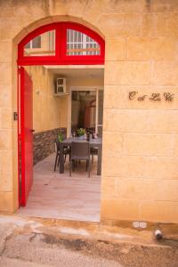 a brick wall with a red door and a dining room at C'Est La Vie in Xagħra