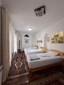 Rumi Hotel & Hostel في بوكسورو: مجموعة من أربعة أسرة في غرفة مع سجادة
