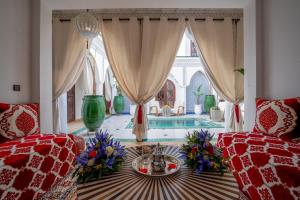 een woonkamer met een tafel en 2 stoelen en een zwembad bij Riad Ekla Boutique Hotel in Marrakesh
