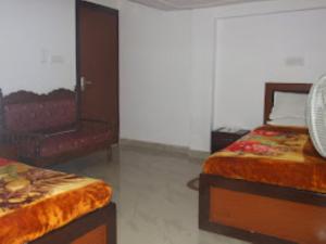 a bedroom with two beds and a chair at Hotel Shiva , Bodh Gaya in Bodh Gaya