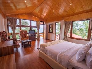 a bedroom with a bed and a desk and windows at Kaya Gantavya Resort in Pelling