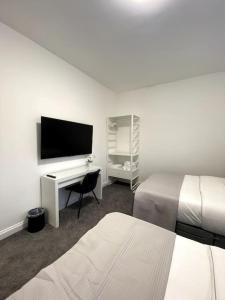 1 dormitorio con 2 camas y escritorio con TV en A home away from home, en Mánchester