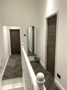 a hallway with a staircase with a mirror and a door at A home away from home in Manchester