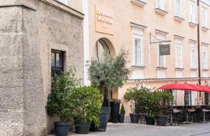 a building with a bunch of potted plants in front of it at Leonardo Boutique Hotel Salzburg Gablerbräu in Salzburg