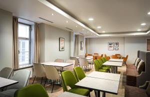 a dining room with tables and green chairs at Leonardo Boutique Hotel Salzburg Gablerbräu in Salzburg