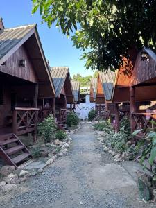 a row of wooden buildings with a dirt road at Benny's House in Pai