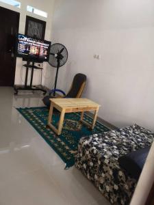 1 dormitorio con cama, mesa y TV en EarlyHome@Adena- Graha Raya en Bendungan