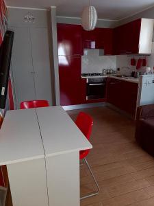 eine Küche mit roten Schränken sowie einem weißen Tisch und Stühlen in der Unterkunft La casetta di Simone in Cassino