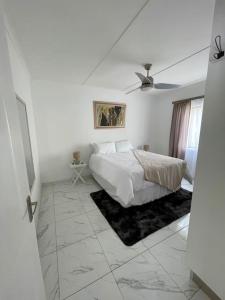 a white bedroom with a bed and a ceiling fan at Luxury 1 Bdr Garden Cottage in Windhoek
