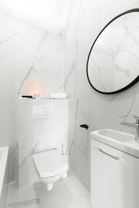 a white bathroom with a toilet and a mirror at Old Town Premium by Elite Apartments in Gdańsk