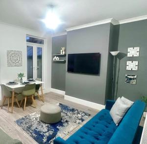 uma sala de estar com um sofá azul e uma mesa em 4BR House for Contractors em New Bilton