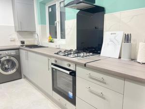 a white kitchen with a stove and a sink at 4BR House for Contractors in New Bilton