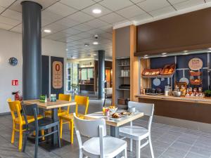 a dining room with tables and yellow chairs at B&B HOTEL Brest Port du Moulin Blanc in Brest