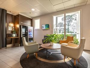 une salle d'attente dans un hôpital avec une table et des chaises dans l'établissement B&B HOTEL Brest Port du Moulin Blanc, à Brest