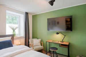 a bedroom with a green wall with a bed and a desk at BLEIBEREI Apartments in Göttingen