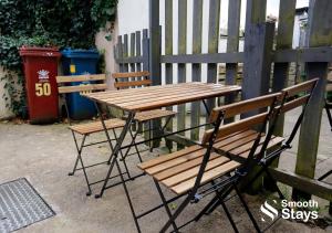 a wooden table and two chairs sitting next to a fence at Stylish 2 Bed House In The Heart Of Clitheroe By Smooth Stays Short Lets & Serviced Accommodation With Parking in Clitheroe