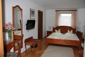 een slaapkamer met een bed, een spiegel en een televisie bij Landhotel St. Florian in Sankt Florian am Inn