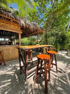 a wooden table and two stools in front of a restaurant at Victory Seaside Home in Bantayan Island