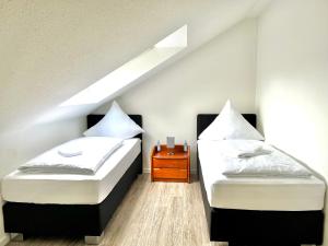 2 Betten in einem Dachzimmer mit einem Nachttisch in der Unterkunft Appart-Haus Business Apartments in Lingen