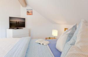 Habitación blanca con cama y TV de pantalla plana. en Ferienhaus Fietje, en Zinnowitz