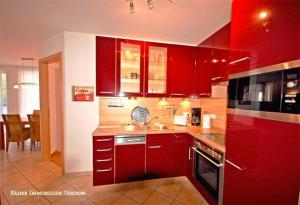 a kitchen with red cabinets and a stove top oven at Ostseeresidenz Gorki Park Nr 01 in Heringsdorf