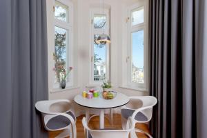 een witte tafel en stoelen in een kamer met ramen bij Villa Gruner Nr 8 in Zinnowitz