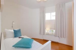 ein weißes Bett mit blauen Kissen in einem Zimmer mit Fenster in der Unterkunft Villa Louise Nr 3 in Ahlbeck