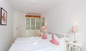 アールベックにあるWeiße Düne Nr 06のベッドルーム(ピンクの枕が付いた白いベッド付)