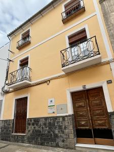 um edifício amarelo com duas varandas e duas portas em Casa Cordón em Montilla