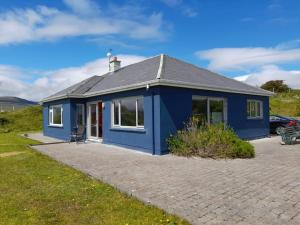 una casa blu in un campo con una macchina di Sandhill, a Mulranny