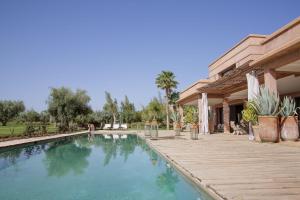 a swimming pool with a wooden deck next to a house at Villa MISH-MISH in Marrakesh