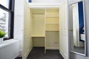 a walk in closet with white cabinets and a window at The Shore in Gourock