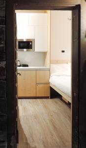 a small kitchen with a bed and white cabinets at Stilla Mini Room in Livigno