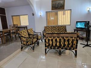 Guesthouse Cocotiers Cotonou في كوتونو: غرفة بها كراسي وطاولة وتلفزيون