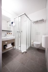 a white bathroom with a shower and a toilet at FairSleep AVIA Motel Zwettl in Zwettl Stadt