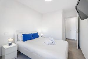 a white bed with blue pillows in a bedroom at Beautifull El Unicornio de Paula in Candelaria
