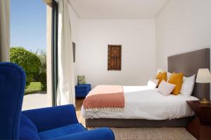 ein Schlafzimmer mit einem Bett und einem blauen Stuhl in der Unterkunft ADA ADA modern villa with heated private pool next city center in Marrakesch