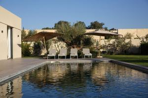 einen Pool mit Stühlen und Sonnenschirmen im Hof in der Unterkunft ADA ADA modern villa with heated private pool next city center in Marrakesch