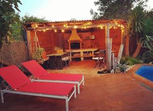een patio met rode stoelen, een tafel en een open haard bij Begur apartamento in Begur